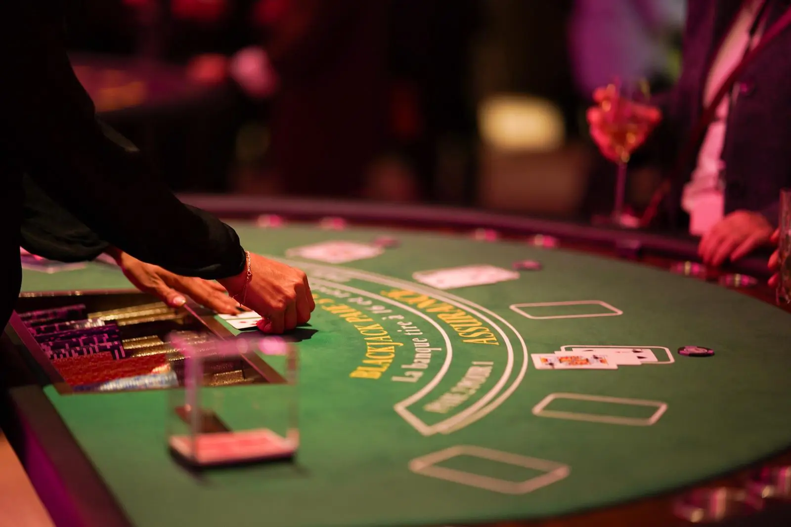 Mains d'une croupière distribuant des cartes sur une table de Blackjack lors d'une soirée casino d'entreprise chez l'As du Casino.