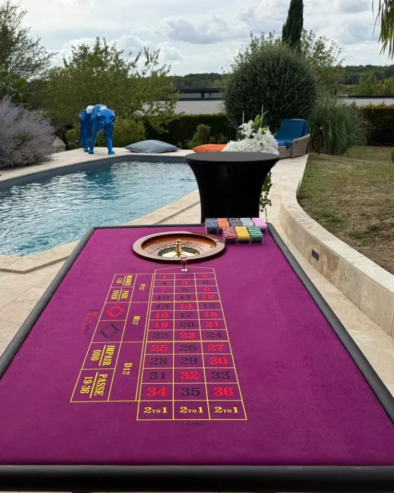 Table de roulette au tapis violet installée au bord d'une piscine pour une fête privée